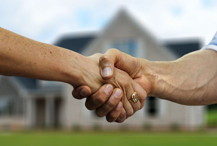 handshake in front of a house
